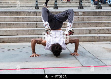 STREET performer. Un acrobatico breakdance busker facendo un handstand nella parte anteriore del ramo principale del New York Public Library sulla Quinta Avenue a Manhattan. Foto Stock