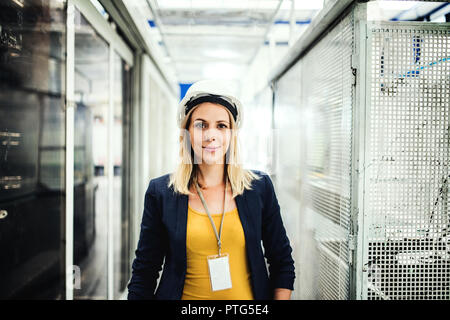 Un ritratto di una donna industriale ingegnere in piedi in una fabbrica. Foto Stock