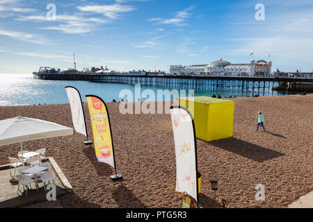 Brighton, Inghilterra, 07 ottobre 2018. La gente sulla spiaggia di Brighton Pier sullo sfondo il mare e la spiaggia di ciottoli di messa a fuoco selettiva Foto Stock