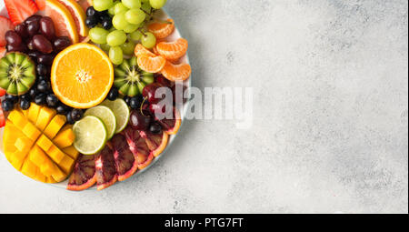 Materie frutti bacche assortimento piatto sulla piastra bianca, bacche di pompelmi e di pomeli Limette di mango arancione sul bianco tabella, vista dall'alto, spazio di copia Foto Stock