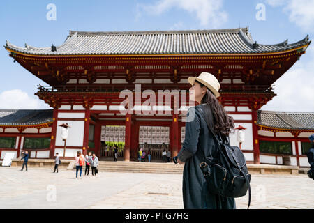 Vista posteriore di un elegante traveler, lei sta portando il suo zaino e passeggiate nel tempio Todaiji Foto Stock