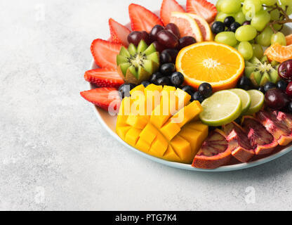Materie frutti bacche assortimento piatto sulla piastra bianca, su off tavolo bianco, copia di spazio, il fuoco selettivo Foto Stock