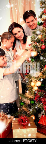 Immagine composita della famiglia felice decorazione di un albero di natale con boubles Foto Stock