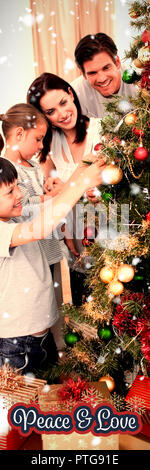 Immagine composita della famiglia felice decorazione di un albero di natale con boubles Foto Stock