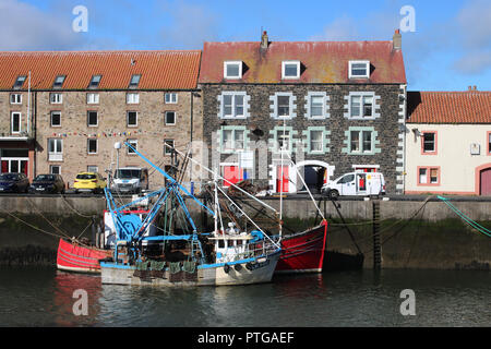 Due piccole barche da pesca legato fino alla banchina del porto in Eyemouth Harbour, Eyemouth, Scozia con edifici sull'altro lato della strada lungo la banchina. Foto Stock