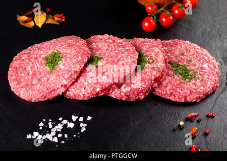 Fresco e carne cruda. Hamburger di carne in macelleria su sfondo nero pronti per la cottura Foto Stock