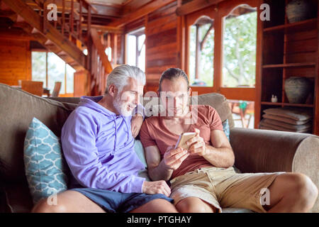 Padre e figlio utilizzando smart phone sul divano di cabina