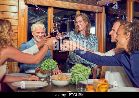 Amici celebrando, bere vino rosso e di gustare la cena in cabina Foto Stock