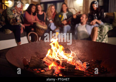 Amici appendere fuori, la riproduzione di brani musicali sul patio accanto a una buca per il fuoco Foto Stock