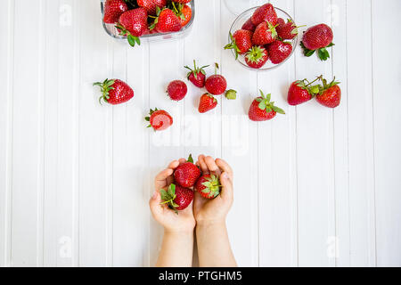 Fragola per la mano di un bambino su uno sfondo bianco Foto Stock