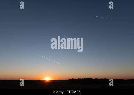 Tramonto con il cielo blu scuro e tracce di piani. Foto Stock