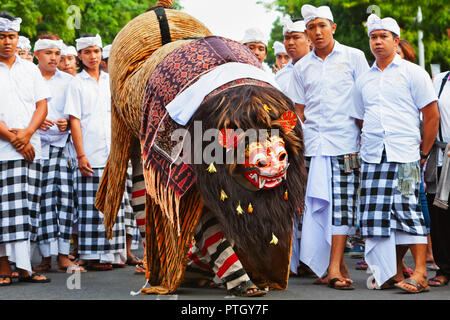 Bali, Indonesia - 23 Giugno 2018: ballerina di uomini in costumi etnici a piedi con maschera tradizionale Balinese di buono spirito Barong sulla cerimonia Indù Ngelawang d Foto Stock