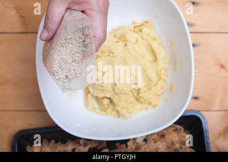 Close up di mani femminili rendendo nocciola cookies da mandorle a fette e la farina con la polvere di caffè . Foto Stock