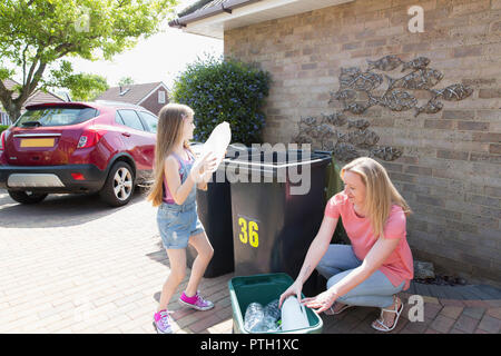 Madre e figlia di plastica riciclaggio fuori casa Foto Stock