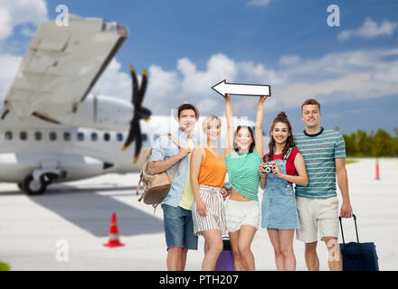 Amici con borse da viaggio e freccia su aereo Foto Stock