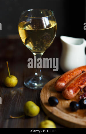 Bicchiere di pera in casa il vino con uno snack. Salsicce alla griglia, formaggio, olive. Menu Ristorante e concetto. Close up Foto Stock