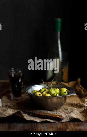 Wild pera in un recipiente di metallo e di vetro bottiglia di vino pera su un di legno scuro dello sfondo. Rustico concetto di spazio di copia Foto Stock