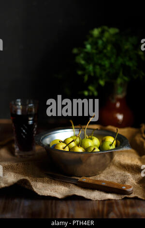 Wild pera in un recipiente di metallo e un bicchiere di pera fatti in casa vino su una tavola di legno vicino sfondo. La vendemmia è delizioso stile rustico Foto Stock