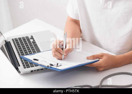 Medico tenere in mano la penna in argento il riempimento la storia del paziente in Elenco appunti pad closeup. Fisica, esame, er, la prevenzione delle malattie, ward round, visita verificare, pr Foto Stock