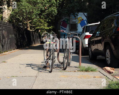 Due le biciclette parcheggiate sul calcestruzzo pavimentazione Urbana di New York Street Foto Stock