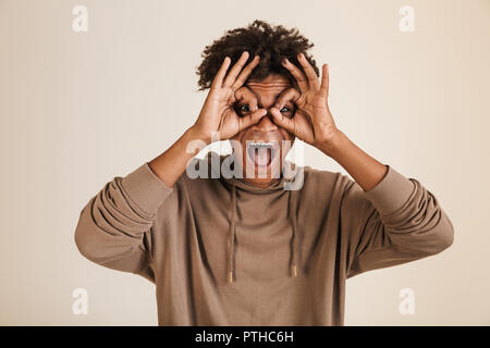 Ritratto di un gioioso giovani afro american uomo vestito di felpa con cappuccio mostra ok isolato Foto Stock