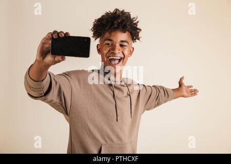 Ritratto di un giovane eccitato afro american uomo vestito di felpa con cappuccio prendendo un selfie isolato Foto Stock