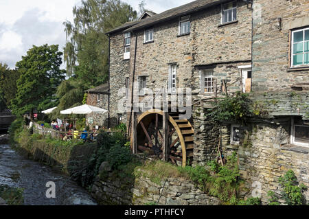 L'Old Mill e le persone che siedono fuori dal ridacchiante caffè Goose in estate Ambleside Cumbria Inghilterra Regno Unito GB Gran Bretagna Foto Stock