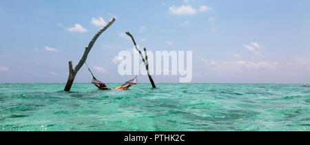 Giovane donna posa in amaca sulla tranquilla oceano blu, Maldive, Oceano Indiano Foto Stock