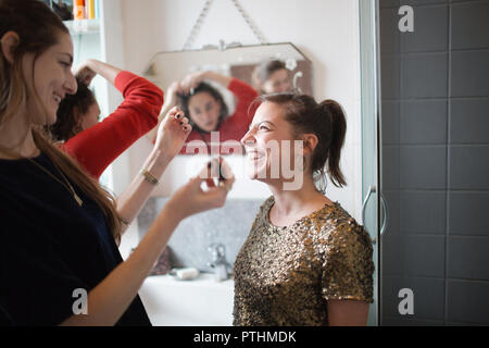 Giovani donne amici ottenere pronto, mettendo il trucco nella stanza da bagno Foto Stock
