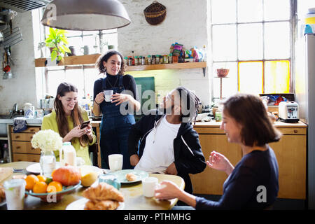 I giovani adulti universitario amici parlando al tavolo per la colazione in appartamento Foto Stock