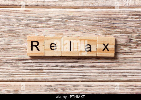 Rilassatevi parola scritta sul blocco di legno. Rilassatevi testo sul tavolo, concetto. Foto Stock
