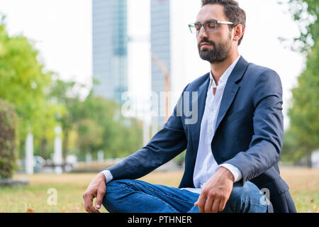 Close-up di calma imprenditore seduta nel parco la meditazione Foto Stock