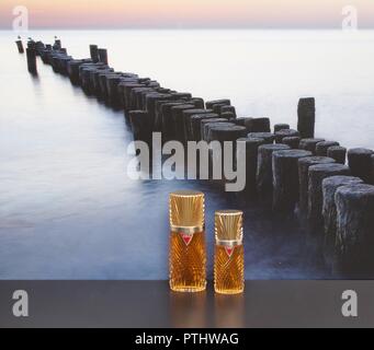 Diva, fragranza per signore, grande bottiglia di profumo accanto a un commerciale bottiglia di profumo di fronte alla foto di un groyne in mare Foto Stock