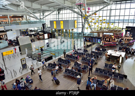 All'interno di Heathrow airport terminal 5 partenze area di attesa con posti a sedere e Flight information board Foto Stock