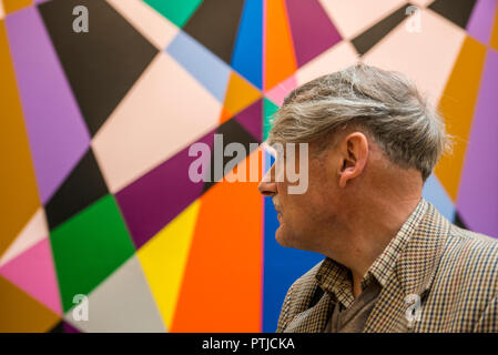 Uomo che guarda verso vivacemente colorate illustrazioni geometrica nella Galleria di Arte Moderna a Leeds. Foto Stock