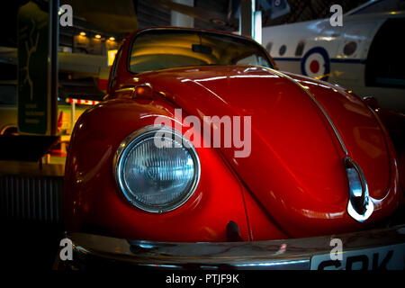 Angolo basso in primo piano di colore arancione chiaro Volkswagen Beetle auto, paraurti anteriore e faro. Foto Stock