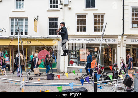 Un animatore di strada a suonare il violino e il bilanciamento su una linea di lasco in Truro City Centre in Cornovaglia. Foto Stock