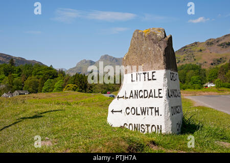 Stone Road Sign vicino a Elterwater con Langdale Pikes in background. Foto Stock