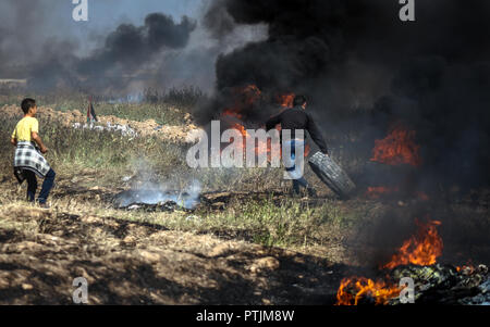 Una foto di manifestanti palestinesi insieme pneumatici sul fuoco durante una dimostrazione lungo la frontiera con Israele. Foto Stock