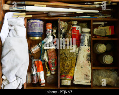 Elementi di un artista per la pittura di olio organizzato su una scatola di legno con i pennelli vernici coltello tavolozza grembiule e altri strumenti Foto Stock