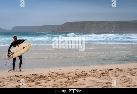 Un surfista passeggiate fuori del mare Foto Stock