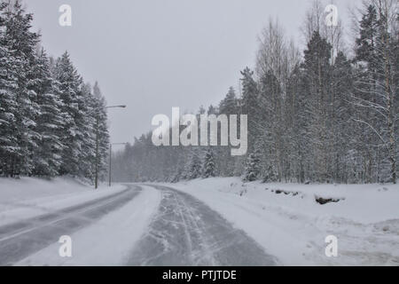 Iced e strade pericolose nel nord in inverno. La neve che ricopre la foresta e la strada Foto Stock