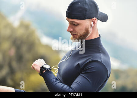 Close-up shot barbuto uomo sportive dopo la sessione di allenamento fitness verifiche dei risultati. Adulto ragazzo indossa Sport Tracker braccialetto. Foto Stock