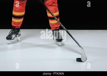 Tagliate di tiro sportivo professionista in pattini giocare hockey su ghiaccio su nero Foto Stock