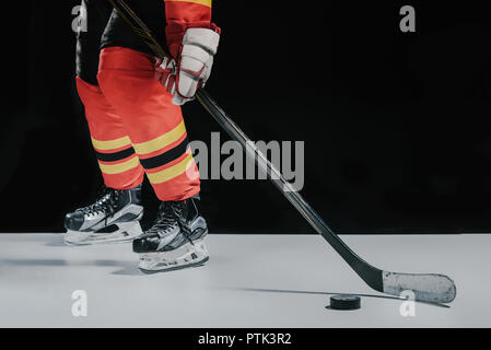 Sezione bassa di sportivo professionista a giocare a hockey su nero Foto Stock