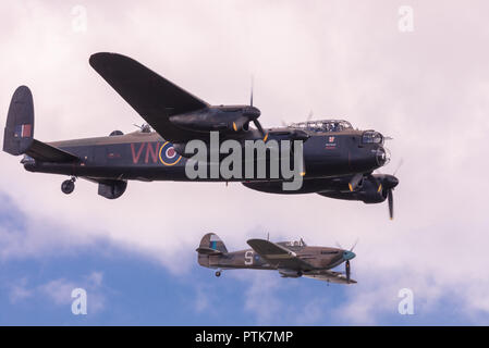 WWII Royal Air Force Avro Lancaster bomber scortato da Hawker Hurricane fighter all'IWM Duxford Air Show. Foto Stock