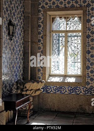 Angolo di un vecchio europeo chiesa cattolica (Porto, Portogallo) con un fonte battesimale in granito e belle piastrelle dipinte sulla parete illuminata da f Foto Stock