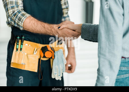 Immagine ritagliata di idraulico e il cliente si stringono la mano in cucina Foto Stock