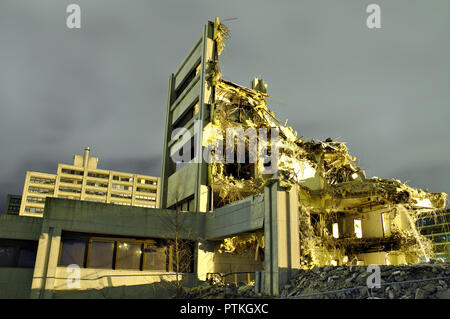 Solo una piccola parte di un edificio distrutto ancora in piedi. Il tetto e la maggior parte dei muri sono crollati. Drammatica scena notturna di un calcestruzzo demolite costruire Foto Stock