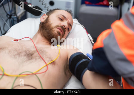 Medico di emergenza controllando la pressione del sangue di un paziente in ambulanza Foto Stock